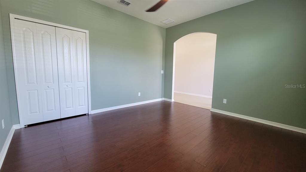 An empty room with sage green walls, dark wood flooring, and a white closet door — 2229 VALTERRA VISTA WAY, VALRICO, FL