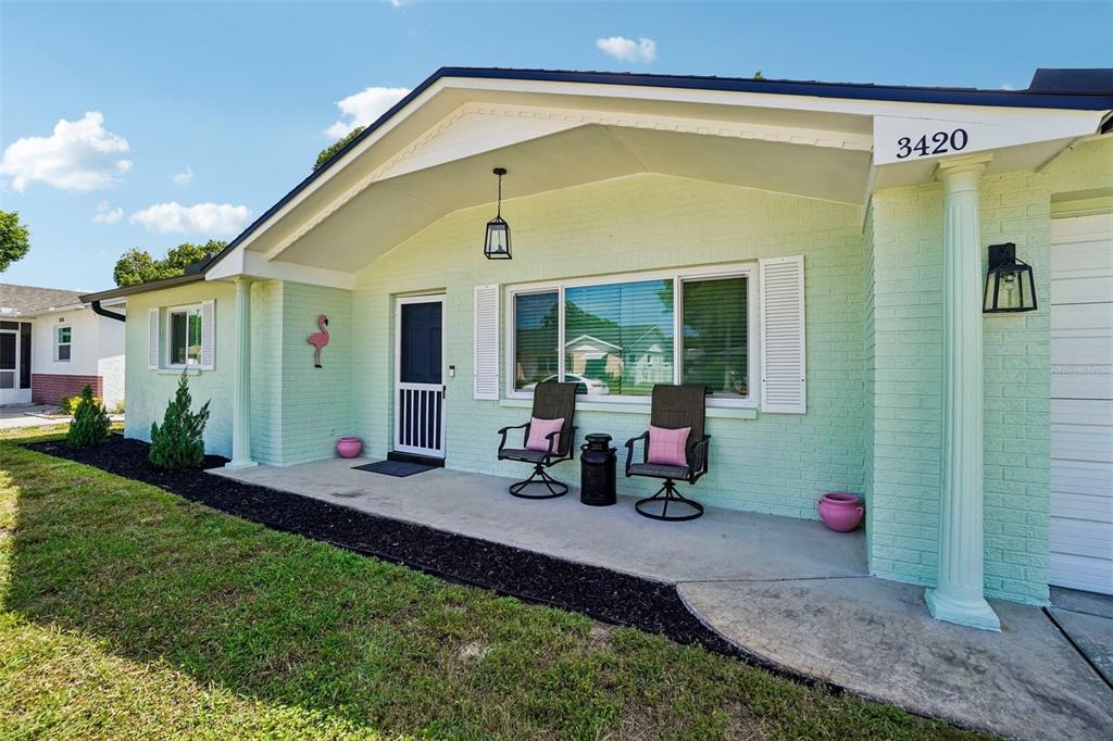 A living room features a dark gray sectional sofa, a television on a console, and wall art — 3420 PALOMA DRIVE, HOLIDAY, FL
