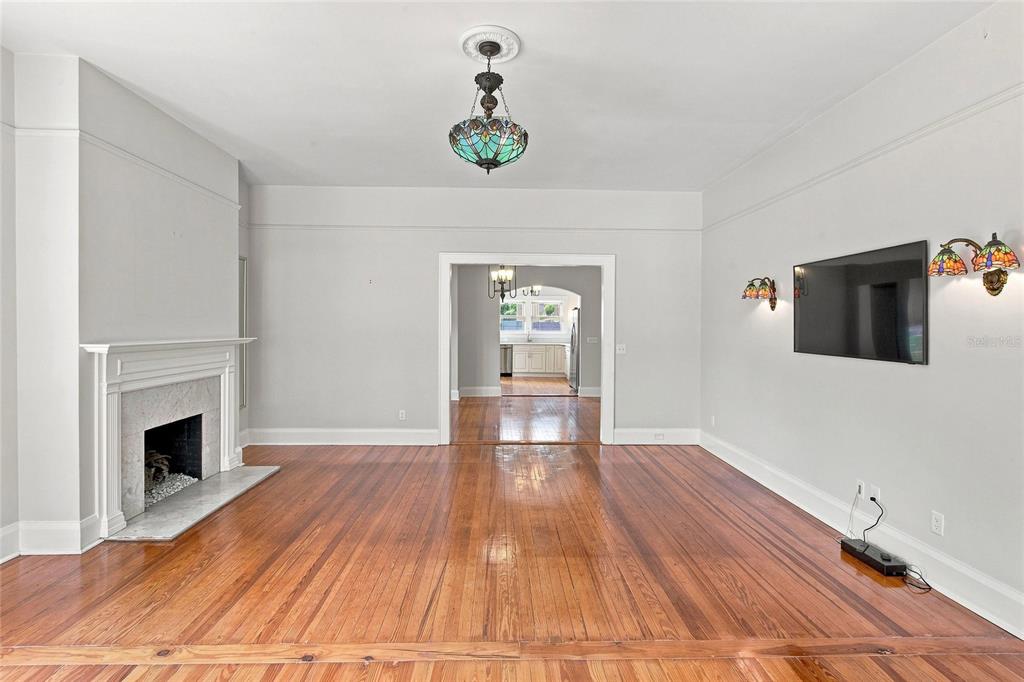 A living room with hardwood floors, a fireplace, a mounted television, and stained-glass lighting fixtures — 929 VISTABULA STREET, LAKELAND, FL