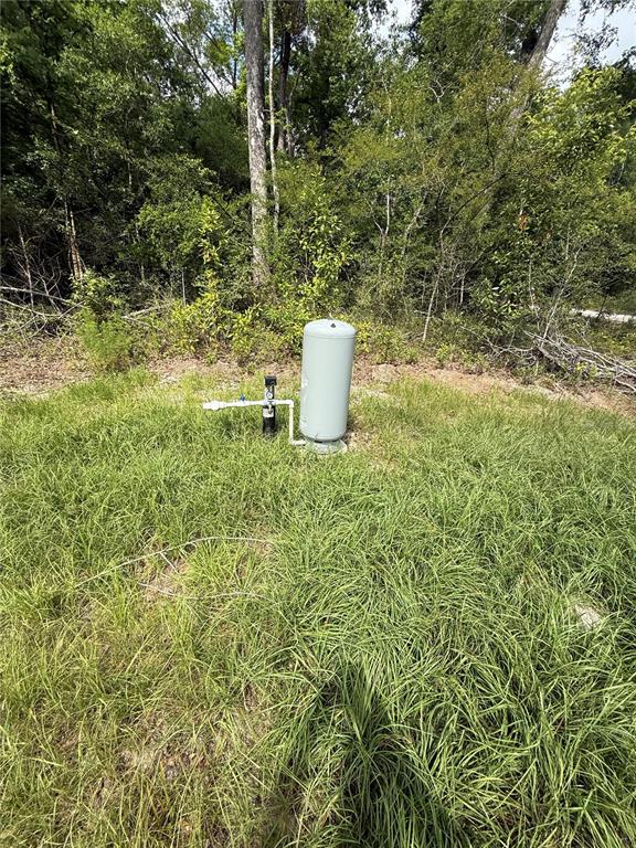 A grey water well pressure tank sits in a grassy field near a wooded area — TBD 292ND ST, BRANFORD, FL
