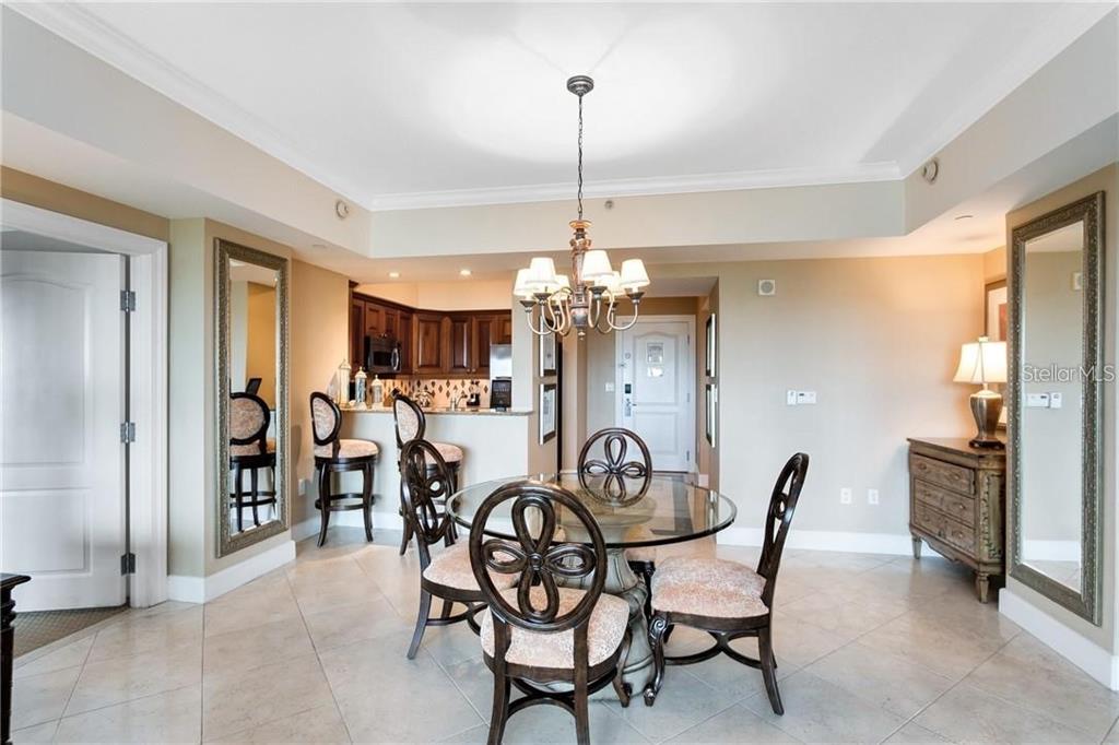 A dining area with a glass table, chairs, and a kitchen counter in the background — 7593 GATHERING DRIVE UNIT 511, REUNION, FL