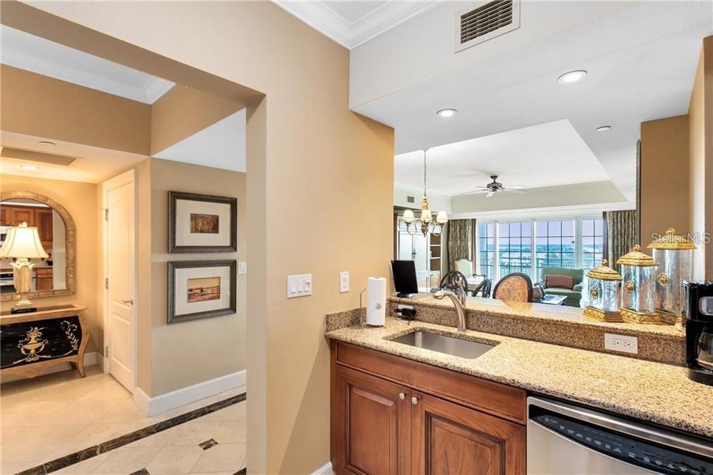 A kitchen sink and granite countertop overlook a living area with a view of water — 7593 GATHERING DRIVE UNIT 511, REUNION, FL