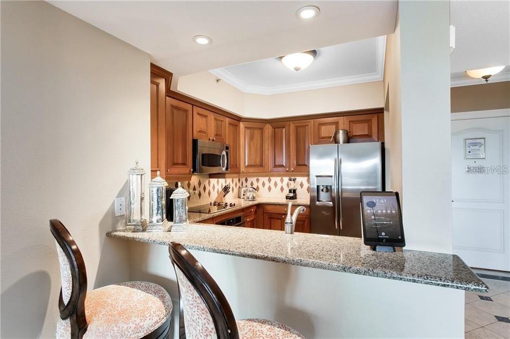 A kitchen features wood cabinets, granite countertops, stainless steel appliances, and a breakfast bar — 7593 GATHERING DRIVE UNIT 511, REUNION, FL