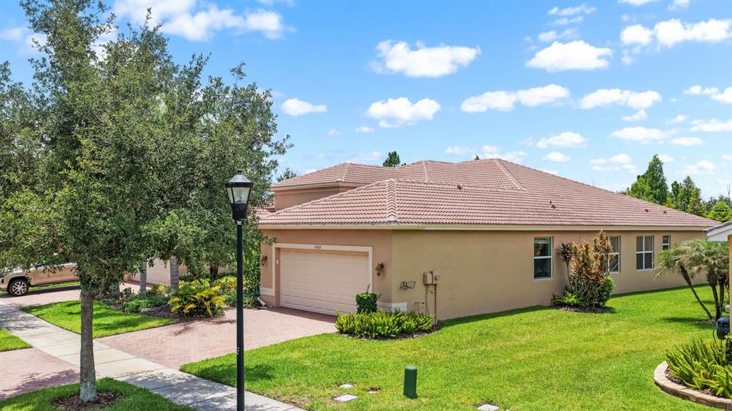 A tan, single-story house with a tile roof and a two-car garage — 15665 AURORA LAKE CIRCLE, WIMAUMA, FL