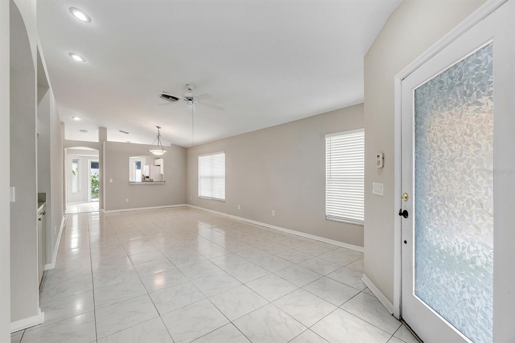 An interior view of a living area with white tile floors, beige walls, and recessed lighting — 8309 QUARTER HORSE DRIVE, RIVERVIEW, FL