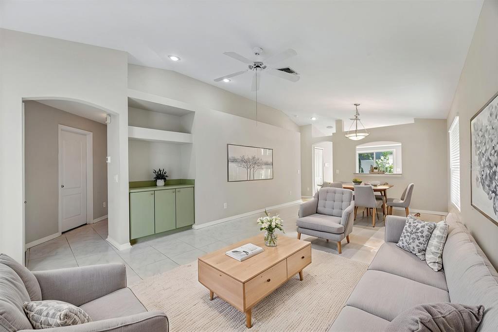 A living room with light tile floors, a wooden coffee table, and sage green cabinetry — 8309 QUARTER HORSE DRIVE, RIVERVIEW, FL