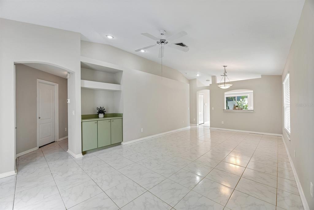 A living area features light-colored tile flooring, a ceiling fan, and a built-in green cabinet — 8309 QUARTER HORSE DRIVE, RIVERVIEW, FL