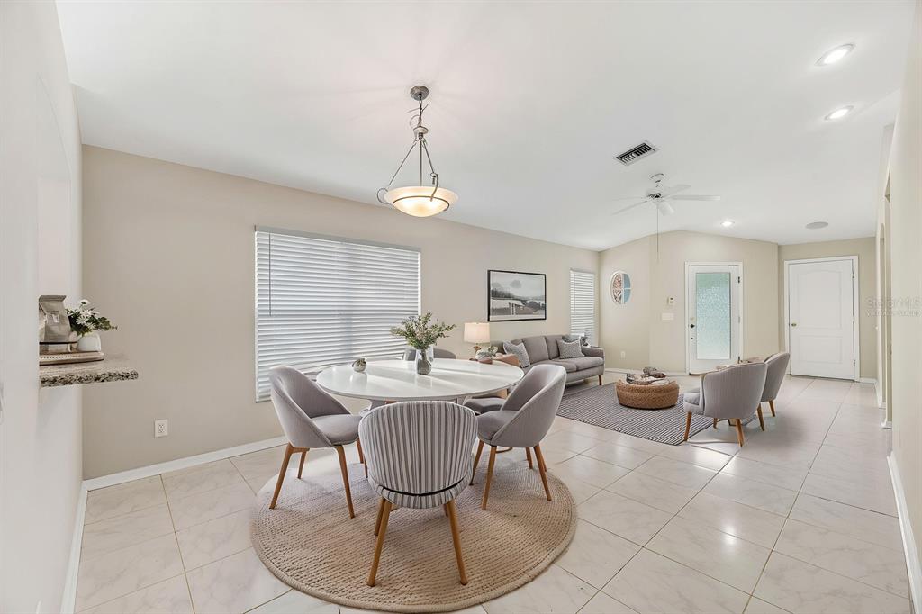 An open-concept dining and living area features tile flooring, a round table, and neutral furniture — 8309 QUARTER HORSE DRIVE, RIVERVIEW, FL