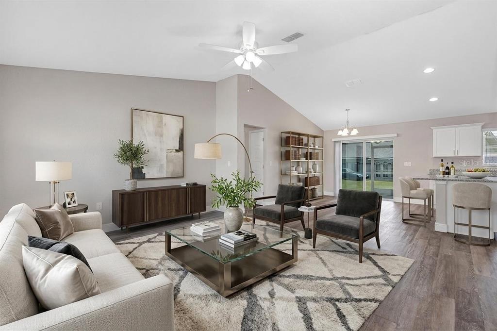 A living room with a vaulted ceiling, neutral furniture, a glass coffee table, and wood flooring — 17 CEDAR TREE RUN, OCALA, FL