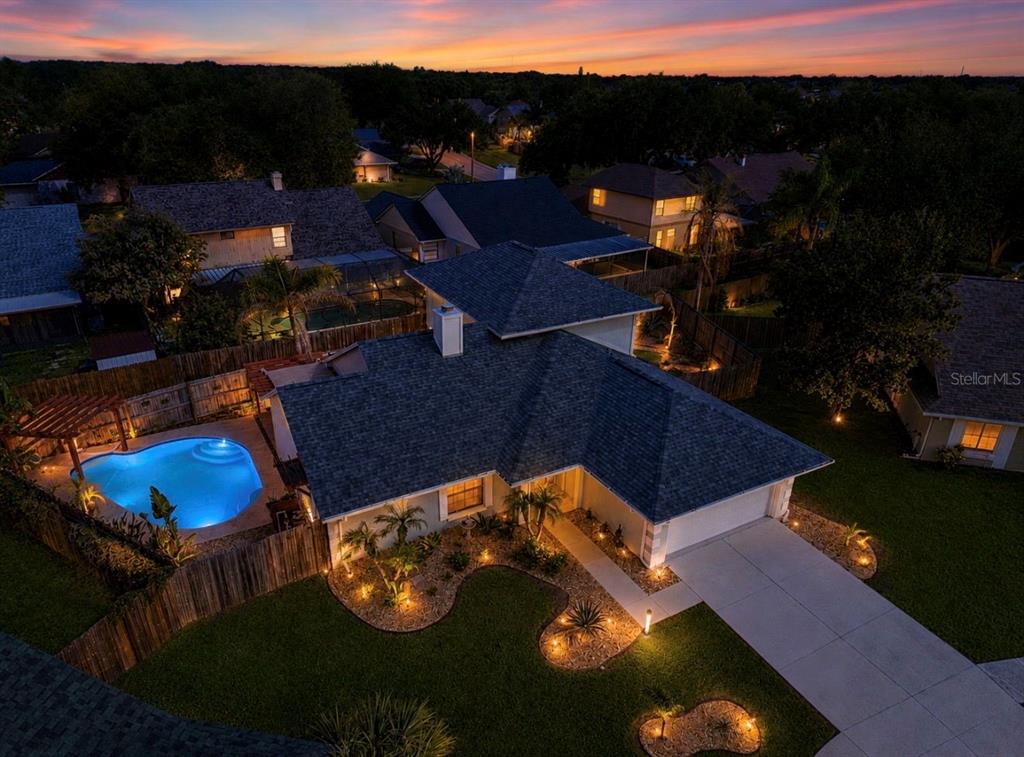 An aerial view of a suburban house at dusk featuring a pool and landscaped yard — 1921 STANFIELD DRIVE, BRANDON, FL