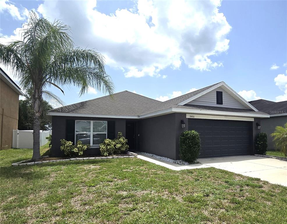 A single-story house with a dark gray exterior, a two-car garage, and a palm tree — 14450 HADDON MIST DRIVE, WIMAUMA, FL