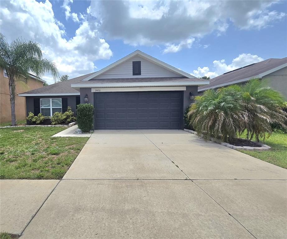 A single-story house with a dark gray garage, a concrete driveway, and two palm trees — 14450 HADDON MIST DRIVE, WIMAUMA, FL
