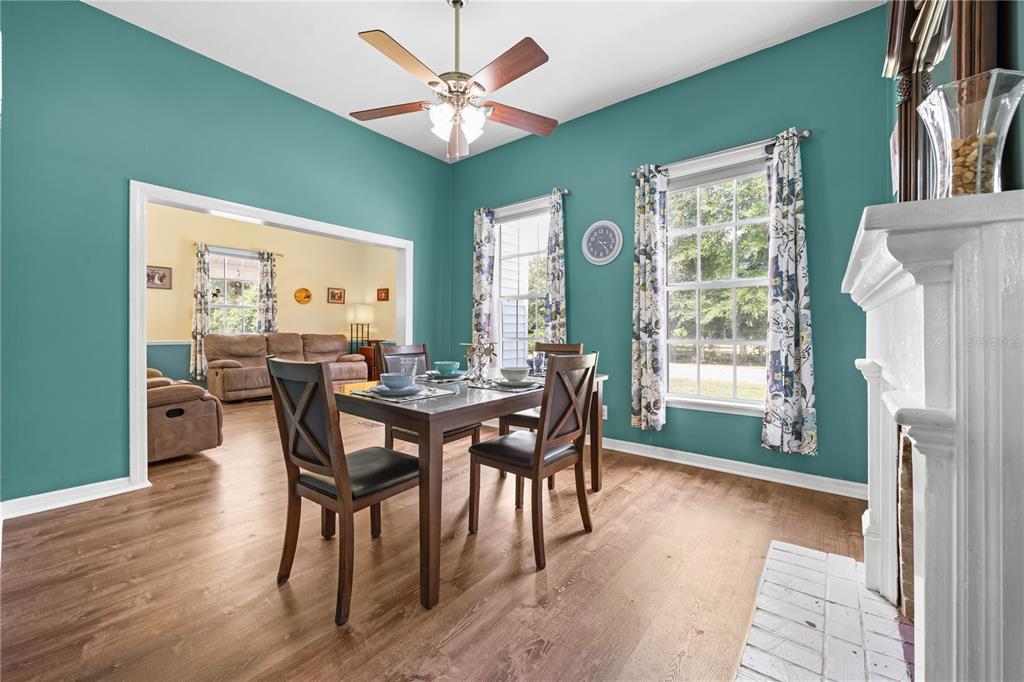 A dining room with teal walls, wood flooring, a ceiling fan, and a fireplace — 1005 11TH AVENUE, WELLBORN, FL