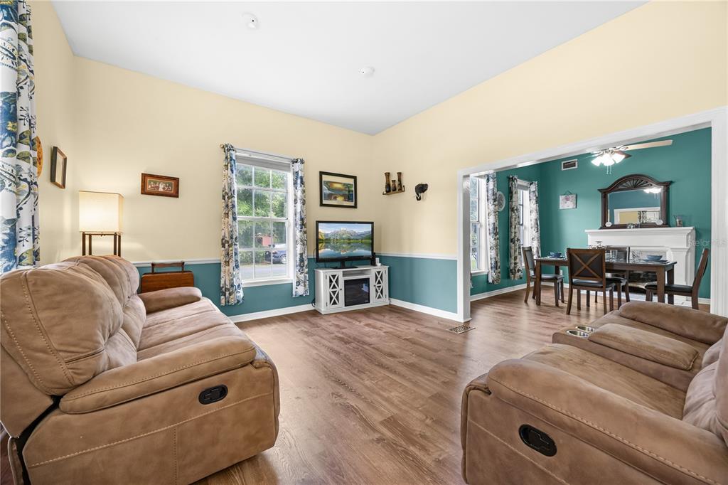 A living room with tan walls, blue wainscoting, two brown sofas, and an adjacent dining area — 1005 11TH AVENUE, WELLBORN, FL