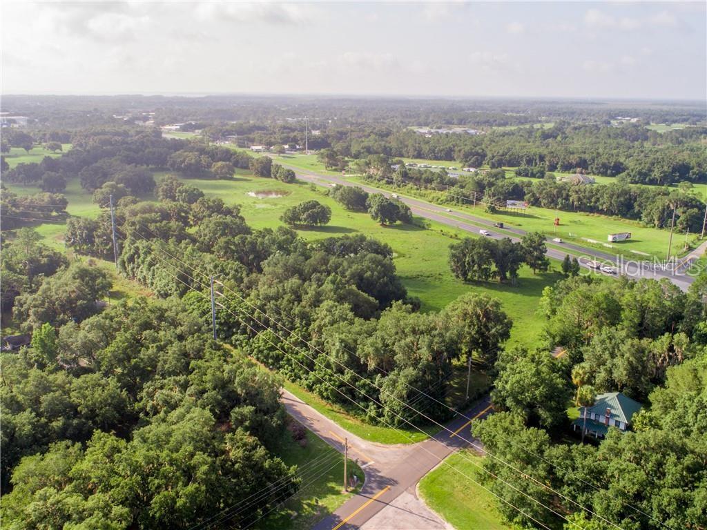 An aerial view of a rural landscape featuring a road intersection, trees, and a house — 1315 SR 44, LEESBURG, FL