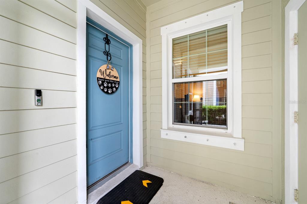 A blue front door with a welcome sign sits next to a window on a porch — 13542 CIRCA CROSSING DRIVE, LITHIA, FL