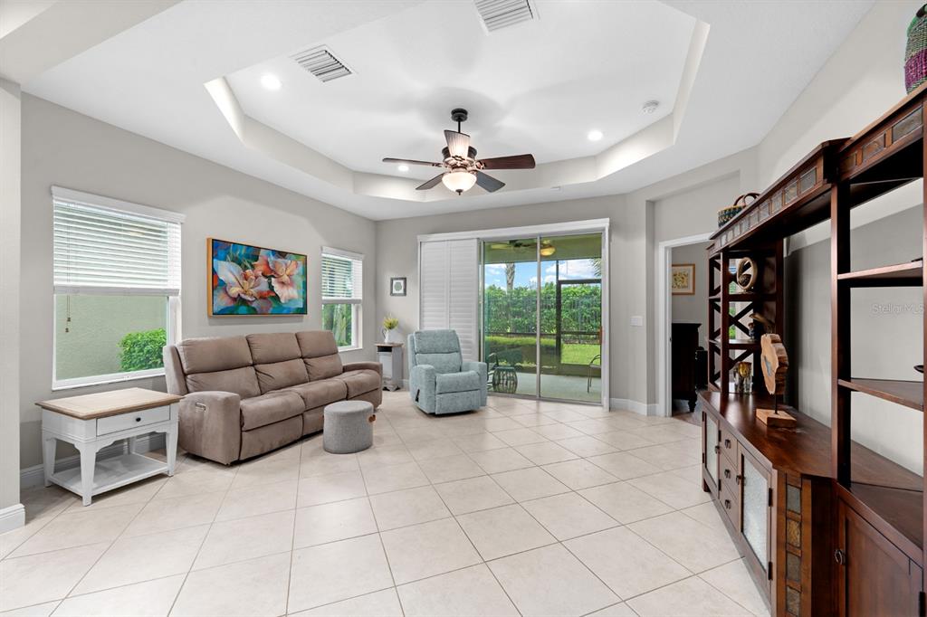A living room features tile floors, a tray ceiling with a fan, and sliding glass doors — 13542 CIRCA CROSSING DRIVE, LITHIA, FL