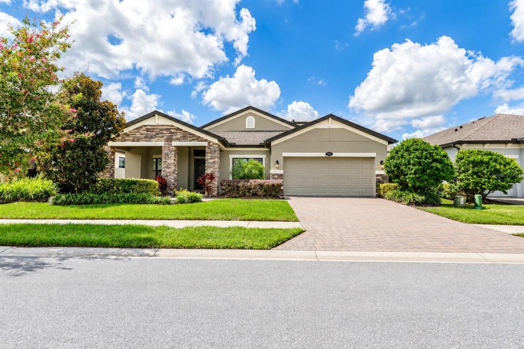 A covered entryway features a dark gray front door, a window, and brick paver flooring — 1741 CHERRY WALK ROAD, LUTZ, FL
