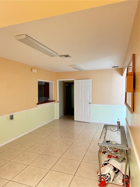 An interior room features tiled floors, two-tone walls, a doorway, and a glass-topped console table — 706 N 7TH STREET, FORT PIERCE, FL