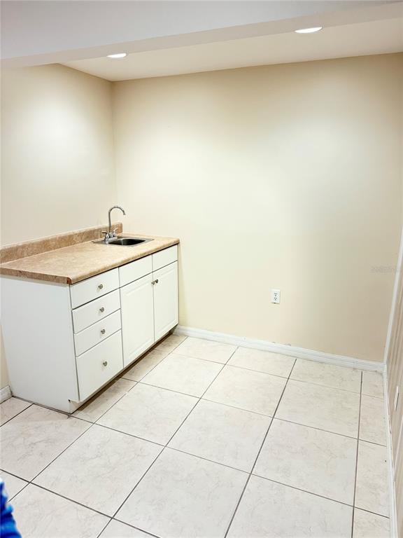 A small kitchenette features white cabinets, a laminate countertop, a sink, and tiled flooring — 706 N 7TH STREET, FORT PIERCE, FL