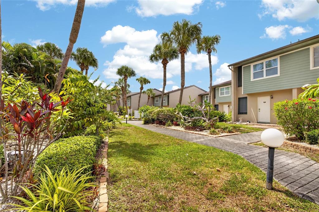 A paved walkway leads past palm trees and landscaping toward a multi-story apartment building — 1028 APOLLO BEACH BOULEVARD UNIT 11, APOLLO BEACH, FL