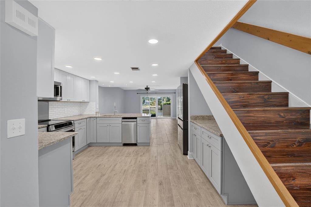 A kitchen with gray cabinets, granite countertops, and wood stairs leading to an upper level — 1028 APOLLO BEACH BOULEVARD UNIT 11, APOLLO BEACH, FL