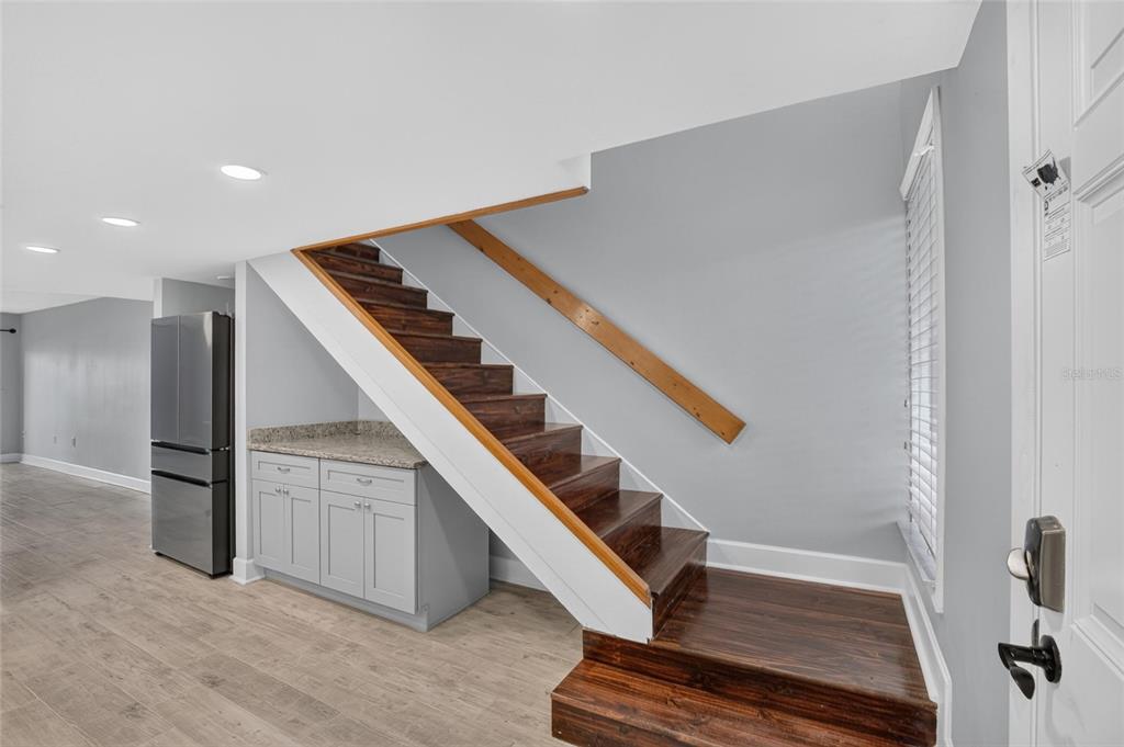 A staircase with dark wood treads and a white handrail sits beside a small kitchen cabinet — 1028 APOLLO BEACH BOULEVARD UNIT 11, APOLLO BEACH, FL