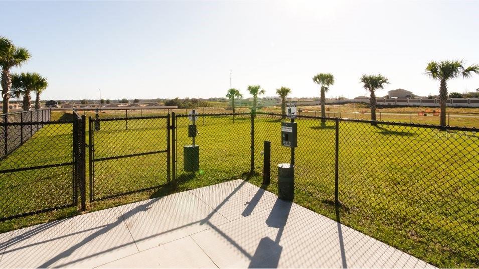 A fenced-in dog park features a concrete patio, waste station, and several small palm trees — 2850 PIONEER TRAIL, EAGLE LAKE, FL