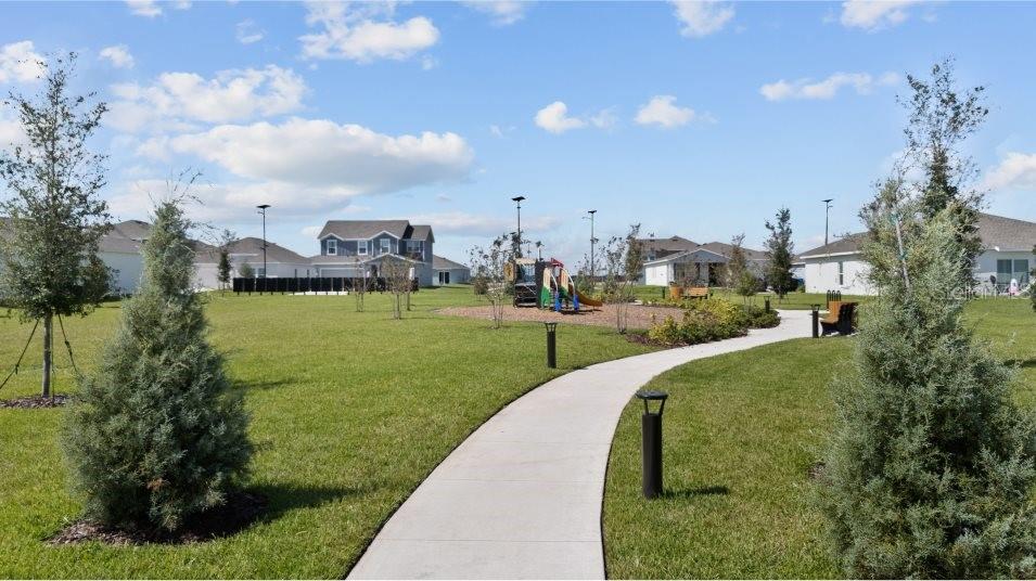 A concrete path leads through a grassy park toward a playground and suburban houses — 2850 PIONEER TRAIL, EAGLE LAKE, FL
