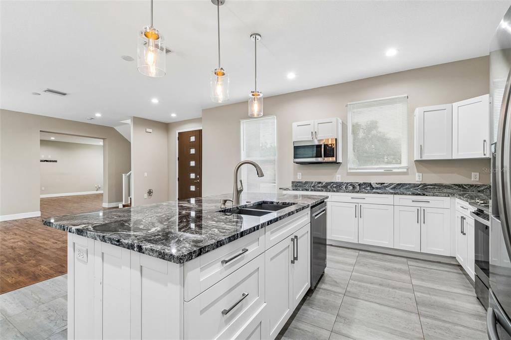 A kitchen with white cabinets, dark granite countertops, a center island, and tile flooring — 8528 PATSY STREET, TAMPA, FL