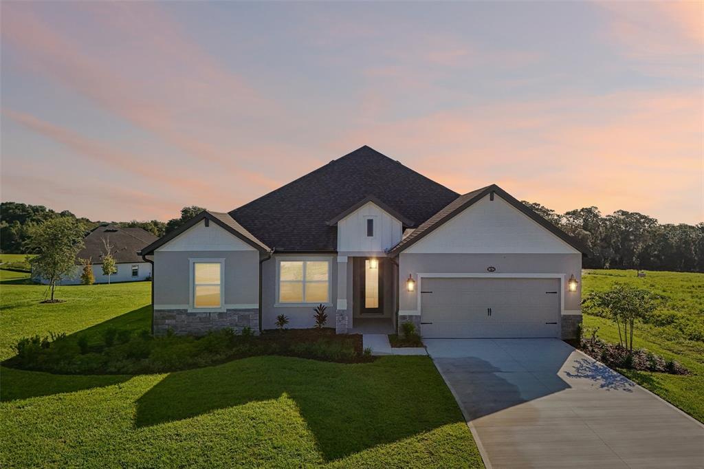 A single-story house with a white stucco facade, stone accents, and a two-car garage — 36794 SUNDOWNER TRAIL, FRUITLAND PARK, FL