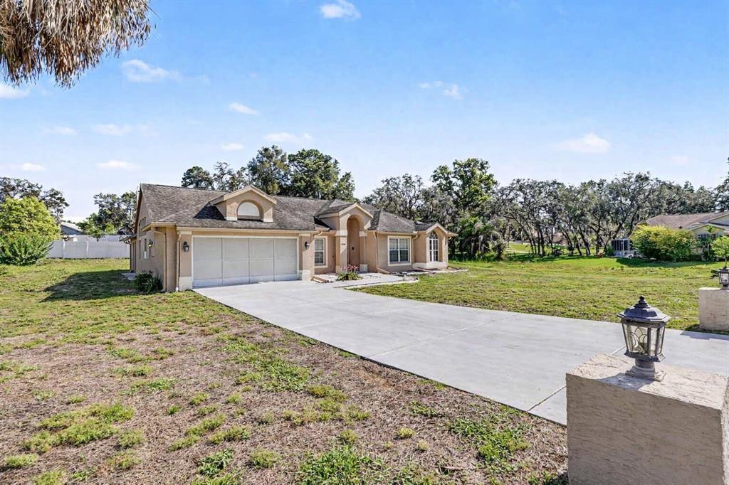 A beige single-story house with a concrete driveway and a multi-car garage — 13037 EVERARD DRIVE, SPRING HILL, FL