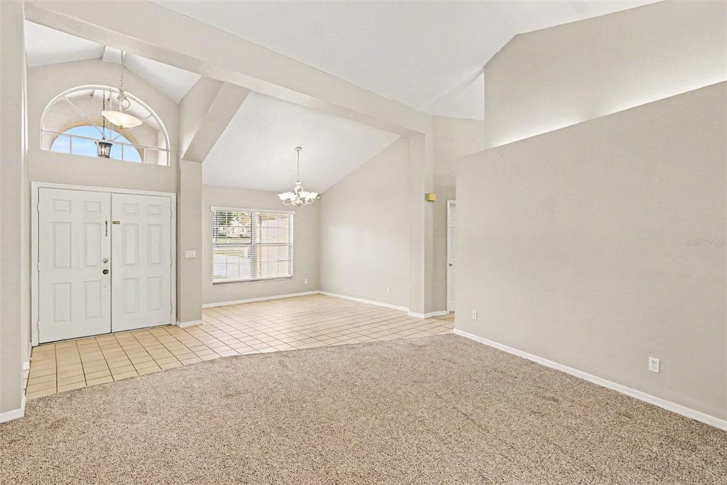 An interior view shows a carpeted living area adjacent to a tiled entryway and dining space — 13037 EVERARD DRIVE, SPRING HILL, FL