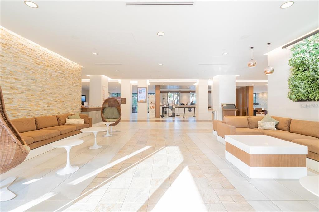 A modern lobby features tan sofas, white coffee tables, a stone wall, and a living wall — 14501 GROVE RESORT AVENUE UNIT 1310, WINTER GARDEN, FL