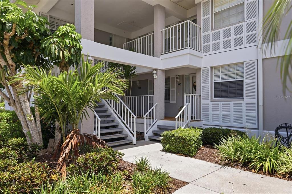 A two-story apartment building exterior features white railings, stairs, and shuttered windows — 1103 EDGEWATER CIRCLE UNIT 1103, BRADENTON, FL