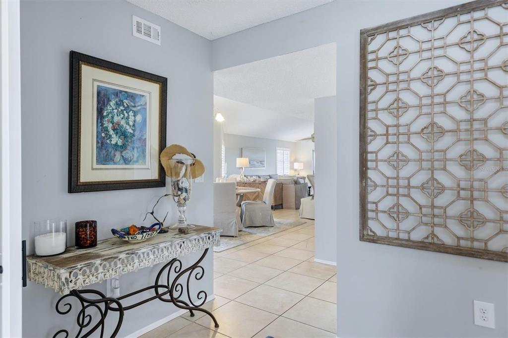 A hallway with a console table leads into a living and dining area with tile floors — 1103 EDGEWATER CIRCLE UNIT 1103, BRADENTON, FL