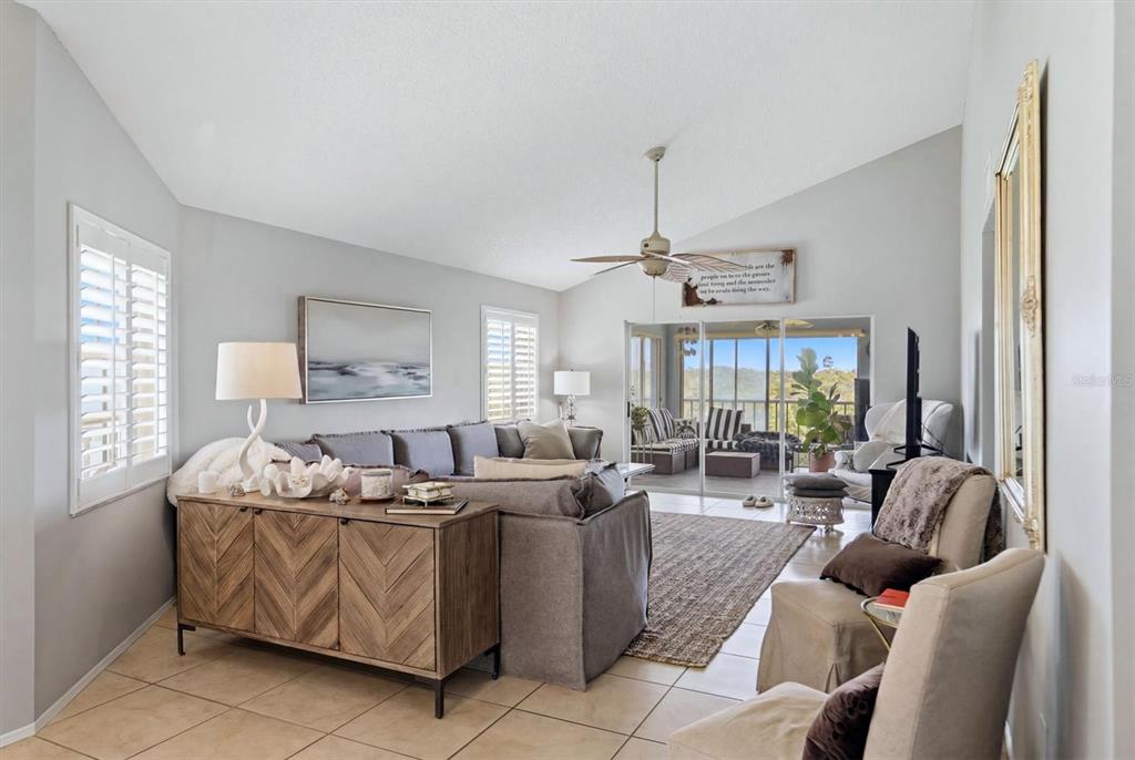 A living room features a grey sectional sofa, a wooden console table, and a sliding door — 1103 EDGEWATER CIRCLE UNIT 1103, BRADENTON, FL