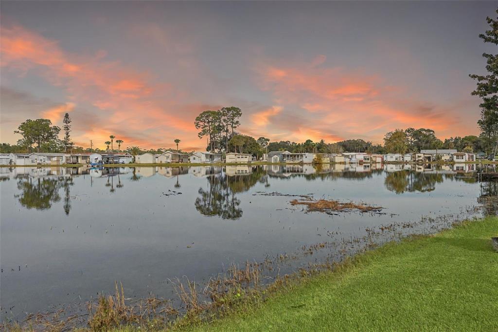A row of mobile homes sits along the edge of a calm lake at sunset — 314 LAKEVIEW DRIVE, OSTEEN, FL