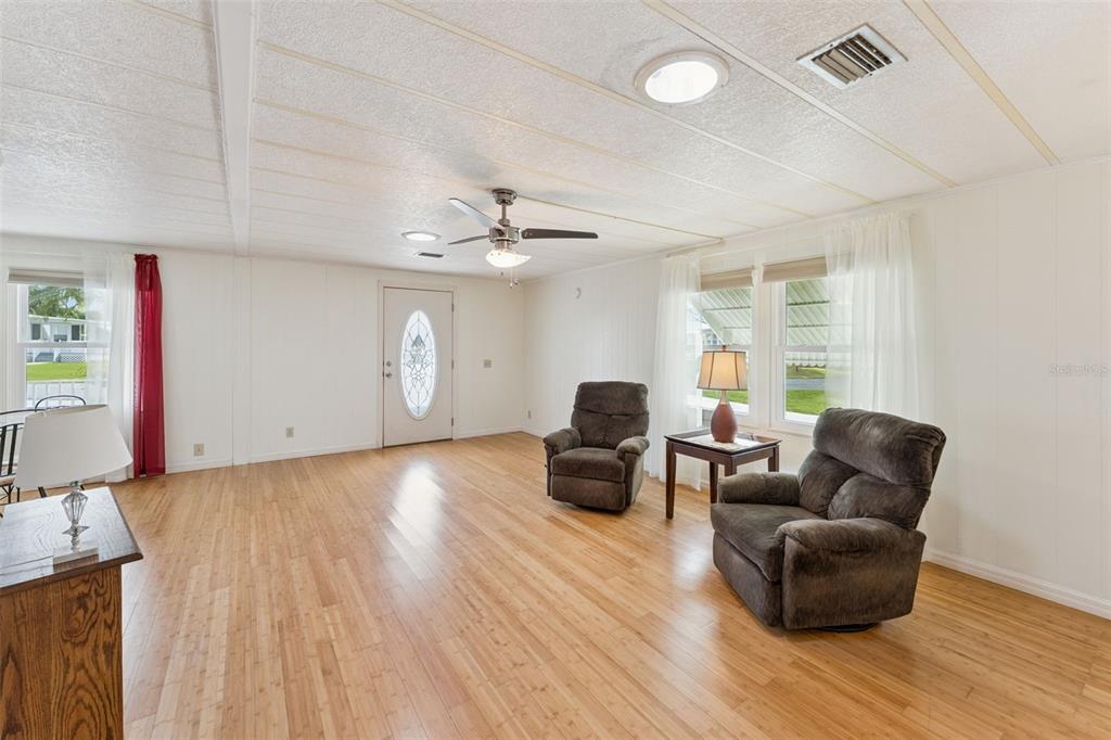 A living room with light wood flooring, two brown recliners, and a ceiling fan — 314 LAKEVIEW DRIVE, OSTEEN, FL