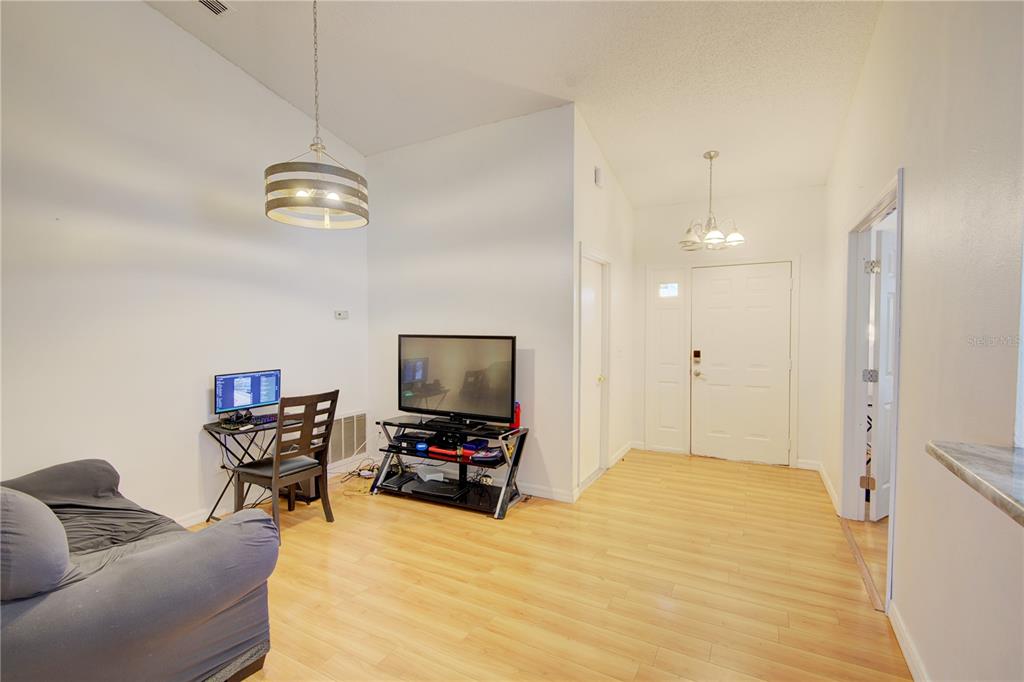 A living room with light wood flooring, a television stand, and a computer desk — 538 QUEENSBRIDGE DRIVE, LAKE MARY, FL