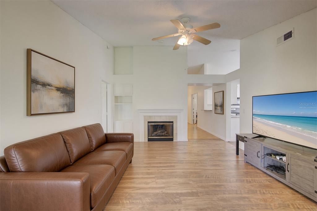 A living room features a brown leather sofa, a fireplace, and a television on a stand — 538 QUEENSBRIDGE DRIVE, LAKE MARY, FL