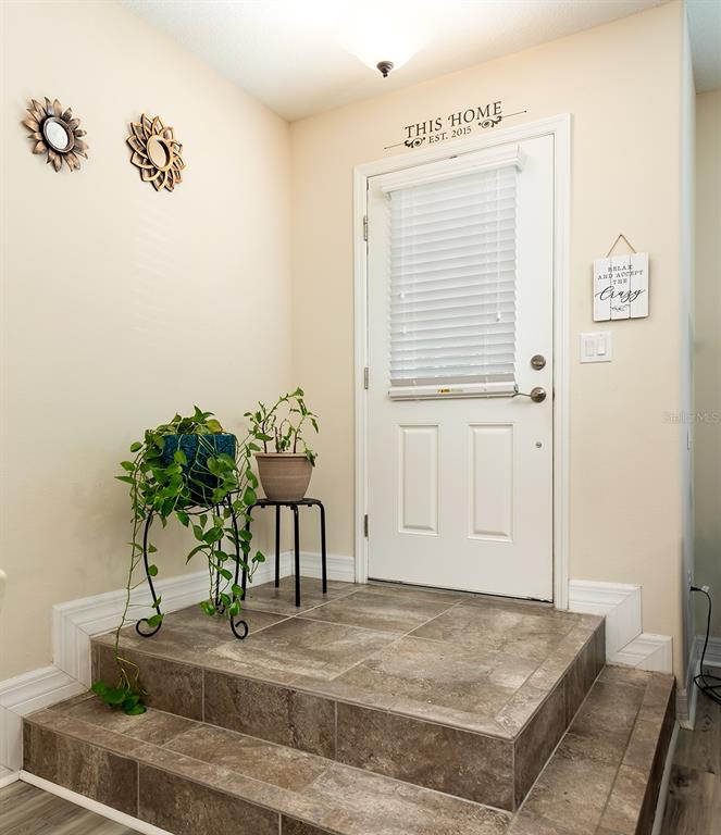 An entryway features a tiled landing with two steps, a white door, and potted plants — 1357 MILL STREAM LANE, WINTER SPRINGS, FL