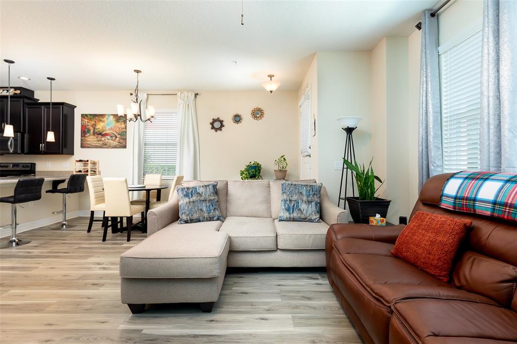 A living room and dining area feature light wood floors, a sectional sofa, and kitchen — 1357 MILL STREAM LANE, WINTER SPRINGS, FL