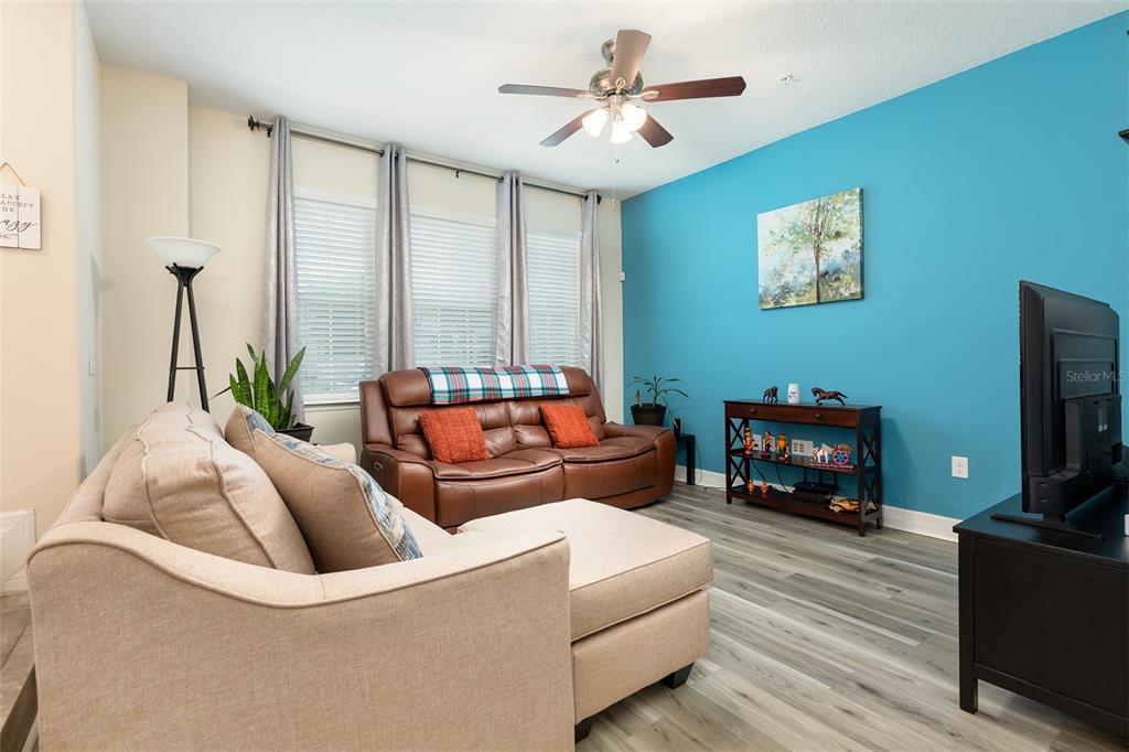 A living room features a beige sectional, brown leather sofa, and a bright blue accent wall — 1357 MILL STREAM LANE, WINTER SPRINGS, FL