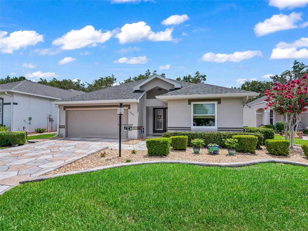 A single-story house with a two-car garage, stone-patterned driveway, and manicured landscaping — 17812 SE 113TH TERRACE, SUMMERFIELD, FL