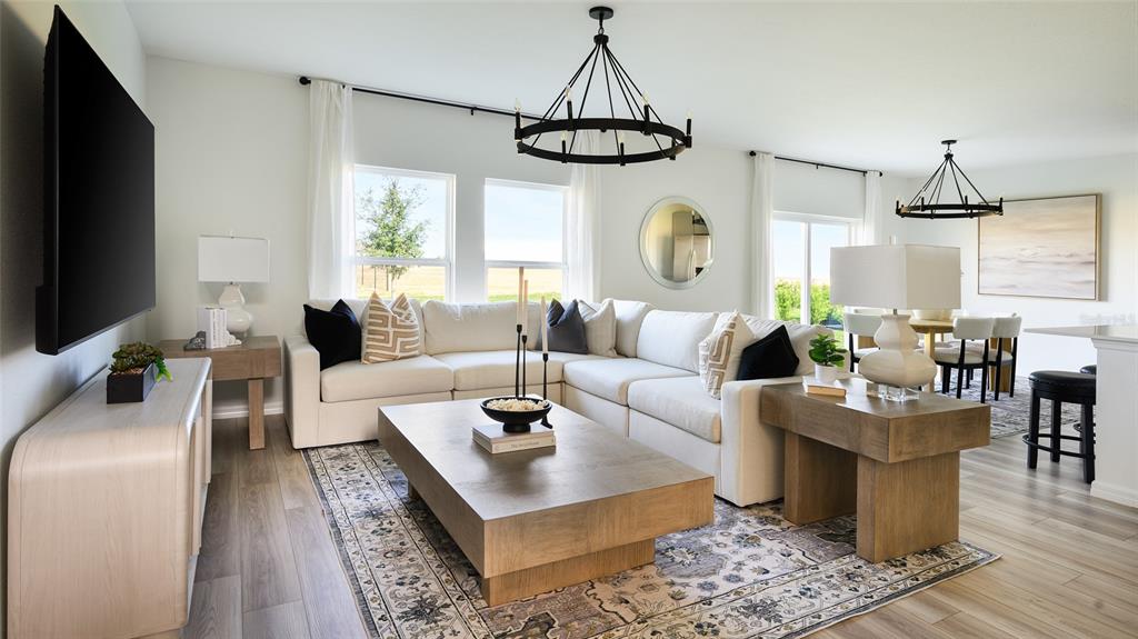 A living room features a white sectional sofa, a wooden coffee table, and two chandeliers — 5377 SAN PIETRO DRIVE, WINTER HAVEN, FL