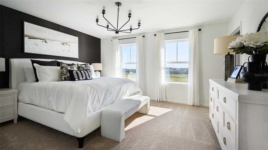 A bedroom features a white bed, a black accent wall, and a white dresser — 5377 SAN PIETRO DRIVE, WINTER HAVEN, FL