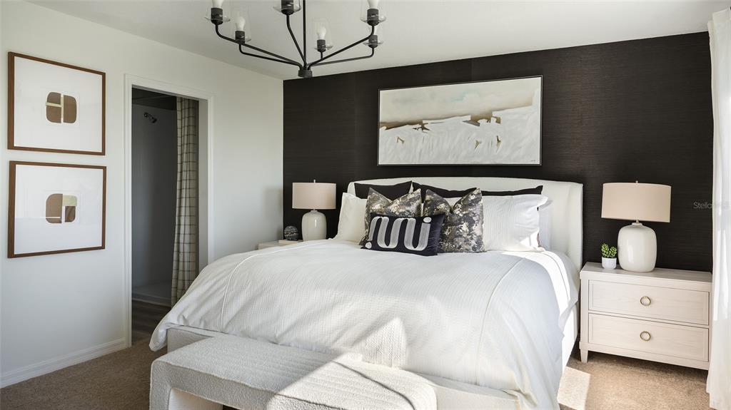 A bedroom features a white bed, a dark accent wall, and a modern chandelier — 5377 SAN PIETRO DRIVE, WINTER HAVEN, FL