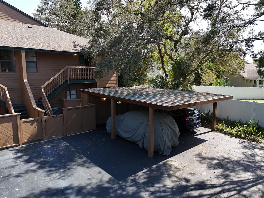 A two-story brown building features an outdoor staircase and a covered carport with a vehicle — 1106 LENNOX ROAD W, PALM HARBOR, FL