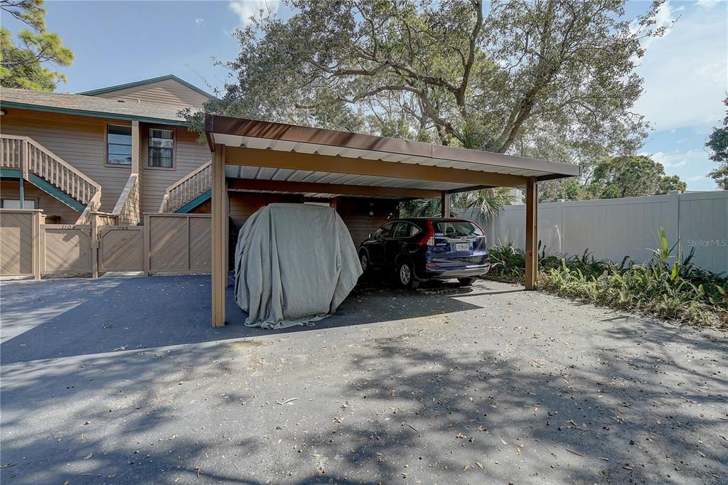 A covered carport with a parked car and a covered object sits beside a building — 1106 LENNOX ROAD W, PALM HARBOR, FL